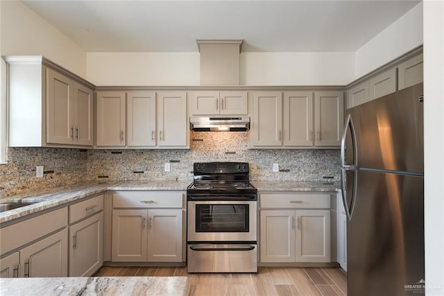 kitchen featuring stainless steel appliances, gray cabinetry, under cabinet range hood, and decorative backsplash