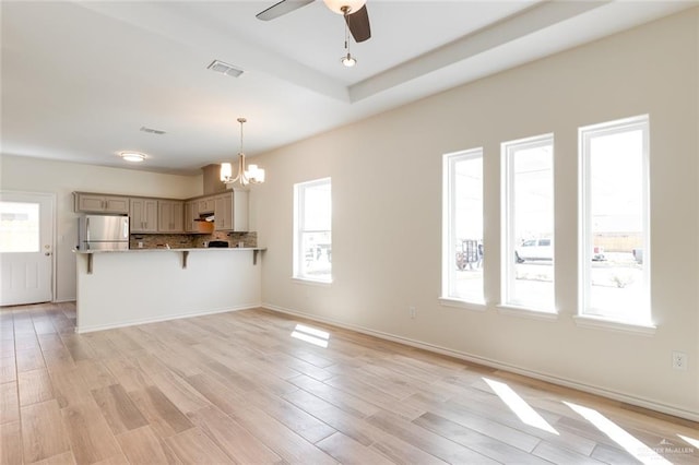 interior space featuring visible vents, light wood finished floors, and ceiling fan with notable chandelier