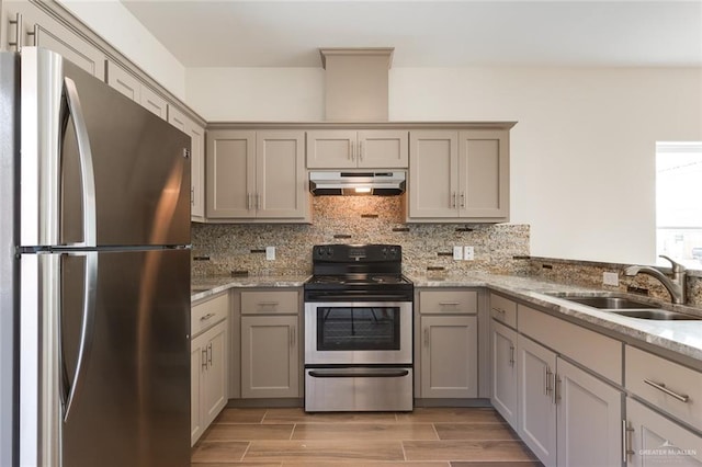 kitchen featuring wood tiled floor, stainless steel appliances, gray cabinetry, under cabinet range hood, and a sink