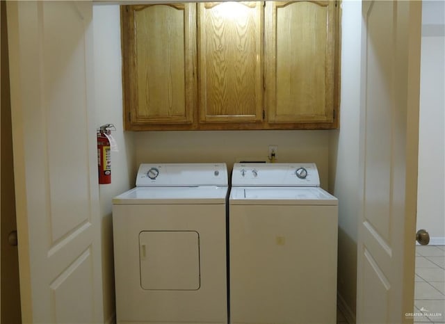 clothes washing area featuring cabinets, separate washer and dryer, and light tile patterned flooring