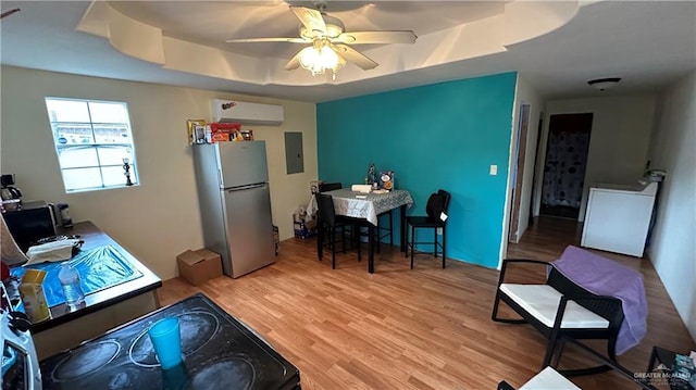 interior space featuring ceiling fan, light hardwood / wood-style flooring, a wall mounted AC, stainless steel fridge, and a tray ceiling