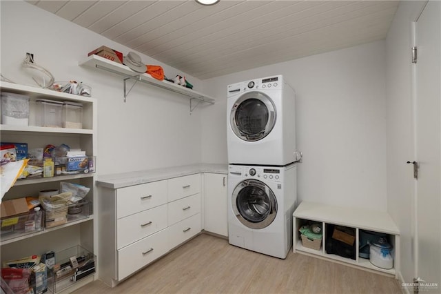 washroom with stacked washer and clothes dryer, light wood-style flooring, cabinet space, and wooden ceiling