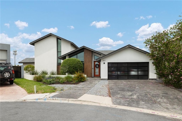 view of front of home with concrete driveway, an attached garage, and stucco siding