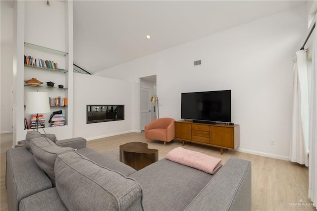 living area with light wood-type flooring, built in shelves, baseboards, and high vaulted ceiling
