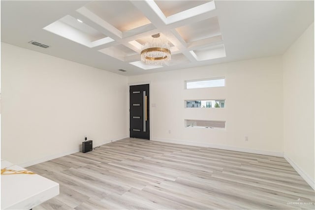 spare room featuring light hardwood / wood-style floors, beamed ceiling, a notable chandelier, and coffered ceiling