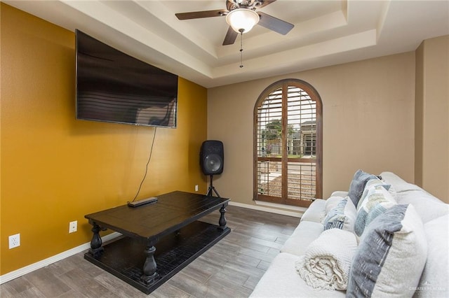 living room featuring hardwood / wood-style floors, a tray ceiling, and ceiling fan