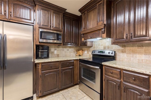 512 Frost Proof Dr, Weslaco, TX 78599 - kitchen featuring stainless steel appliances, backsplash, light tile patterned floors, and dark brown cabinetry