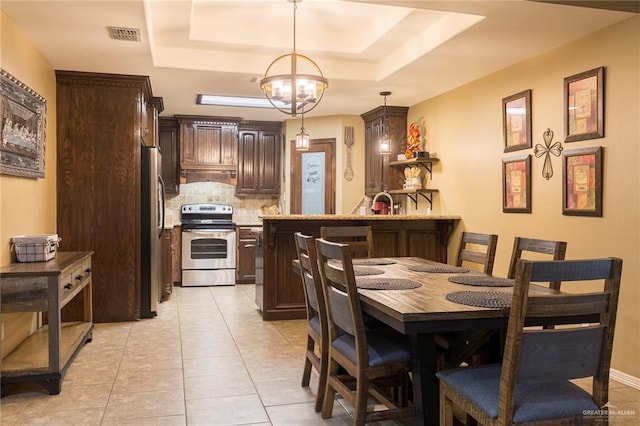 tiled dining room with a tray ceiling and an inviting chandelier