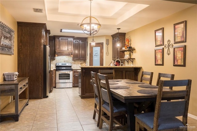 512 Frost Proof Dr, Weslaco, TX 78599 - dining area with a tray ceiling, a chandelier, and light tile patterned flooring