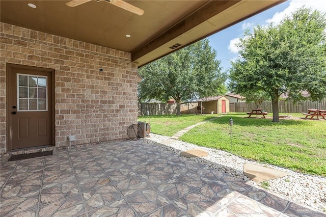 view of patio with ceiling fan and a shed