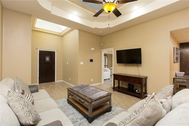 living room with a raised ceiling and ceiling fan