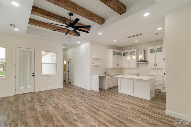 2211 Tomatillo Dr, Weslaco, TX 78596 - kitchen featuring wall chimney range hood, light wood finished floors, a center island, beam ceiling, and open floor plan