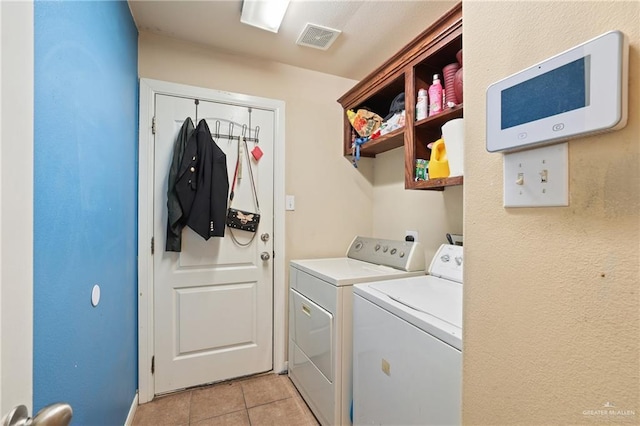washroom featuring laundry area, light tile patterned flooring, visible vents, and washer and clothes dryer