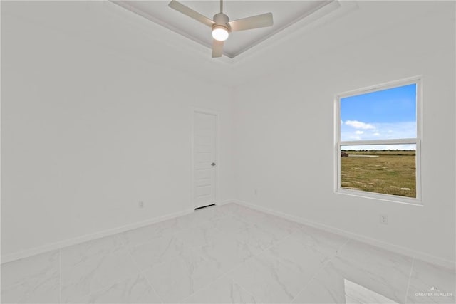 unfurnished room with a tray ceiling, marble finish floor, ceiling fan, and baseboards