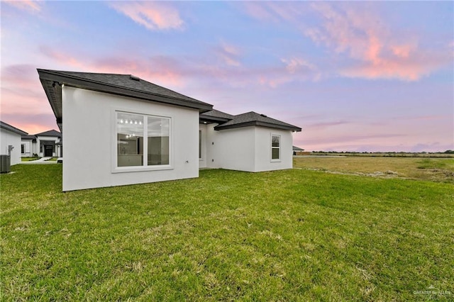 back of property with a lawn, cooling unit, and stucco siding