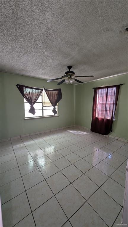 unfurnished room featuring ceiling fan, light tile patterned floors, and a textured ceiling