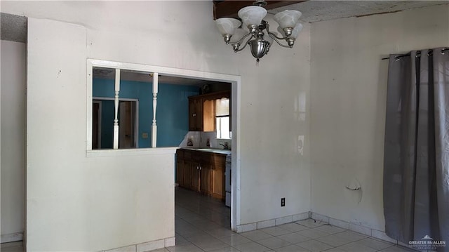 tiled empty room featuring a notable chandelier