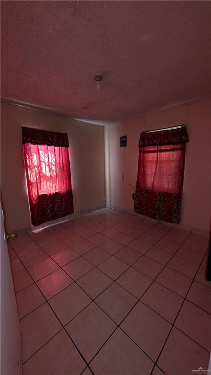 unfurnished room with tile patterned flooring and a textured ceiling