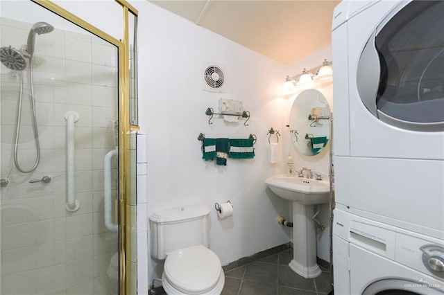 bathroom featuring toilet, tile patterned floors, an enclosed shower, and stacked washer and clothes dryer