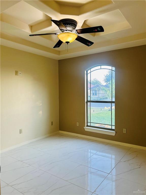 spare room featuring ceiling fan and a raised ceiling