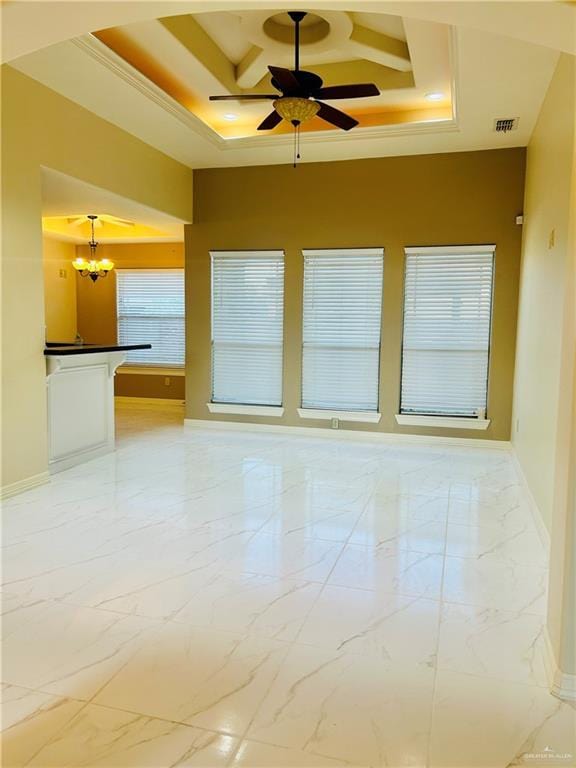 spare room with a towering ceiling, a tray ceiling, and ceiling fan with notable chandelier