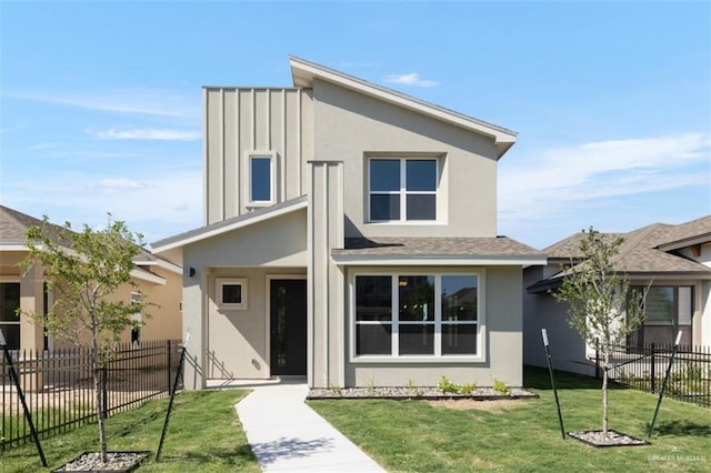 view of front of property with stucco siding, a front lawn, fence, and a shingled roof