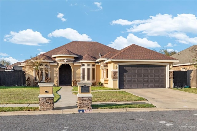 view of front facade with stucco siding, fence, concrete driveway, a front yard, and a garage