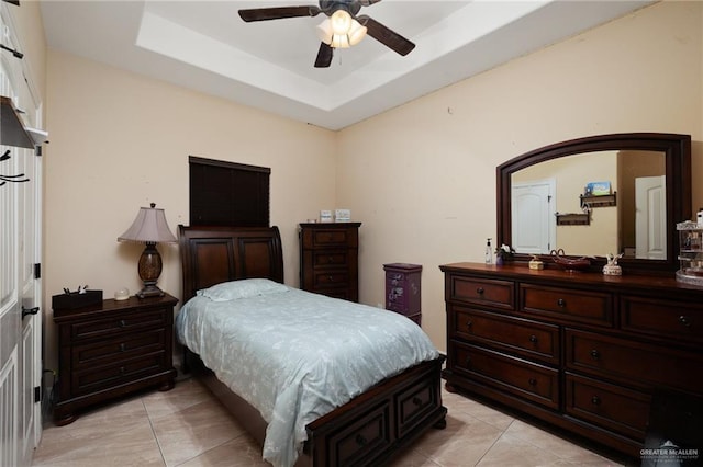 bedroom featuring light tile patterned floors, a ceiling fan, and a tray ceiling