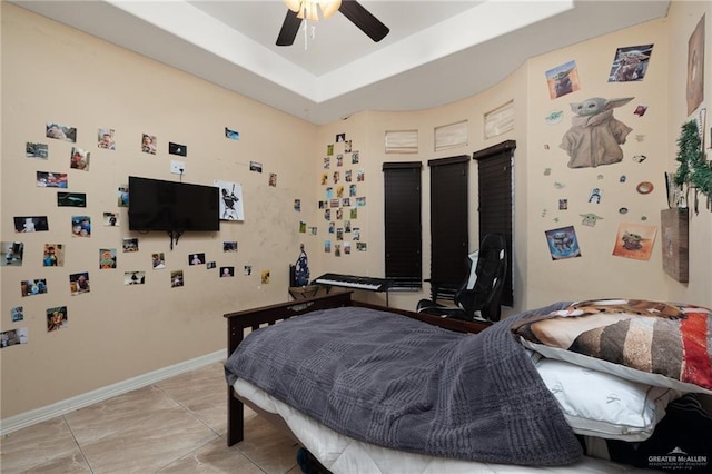 bedroom featuring baseboards, a raised ceiling, and a ceiling fan