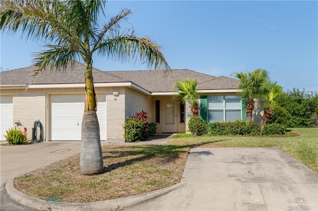 view of front of property featuring a garage, a front yard, brick siding, and driveway