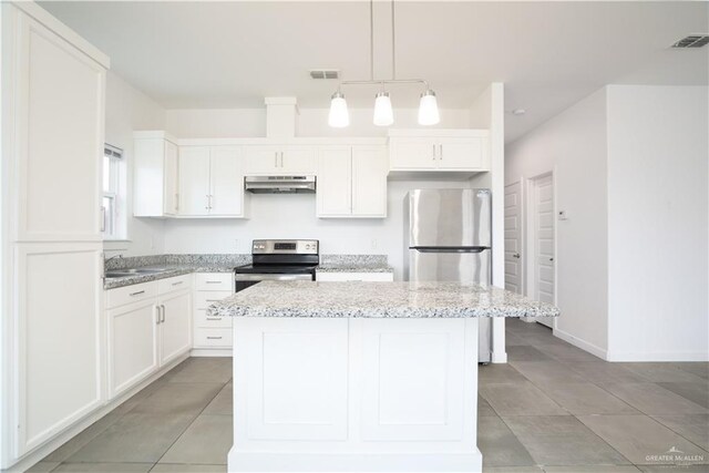 kitchen with a center island, white cabinets, hanging light fixtures, appliances with stainless steel finishes, and light stone counters