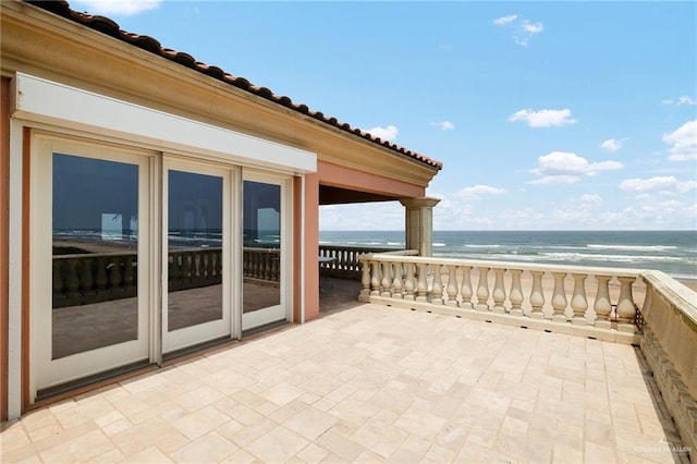 view of patio / terrace with a water view and a beach view