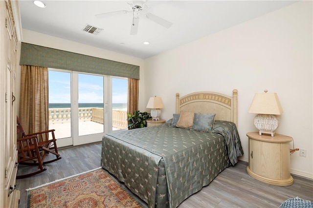 bedroom featuring access to outside, ceiling fan, a water view, and wood-type flooring