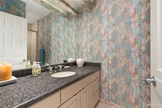 bathroom with tile patterned flooring, vanity, and walk in shower