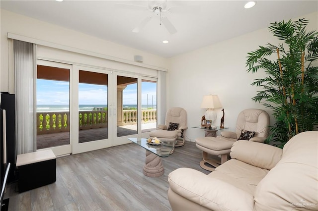 living room with a water view, light hardwood / wood-style floors, plenty of natural light, and ceiling fan