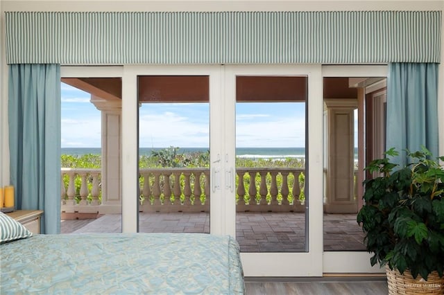 bedroom featuring access to outside, a water view, and hardwood / wood-style floors