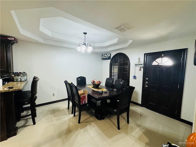 dining space featuring a notable chandelier, light tile patterned floors, and a tray ceiling