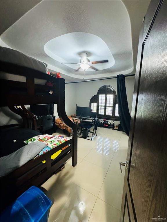 bedroom with a tray ceiling, tile patterned floors, and ceiling fan