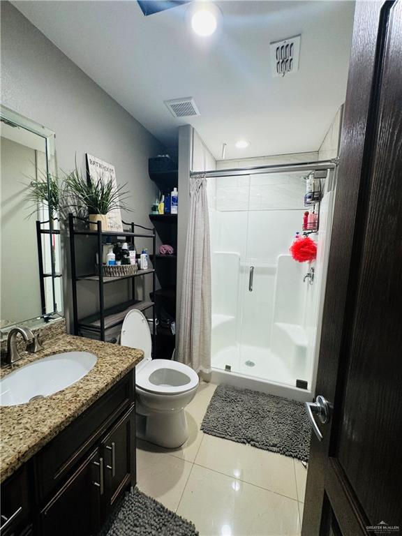 bathroom featuring toilet, vanity, tile patterned floors, and curtained shower