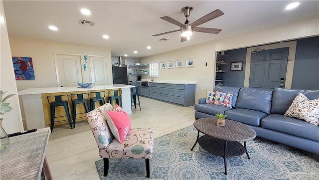 living room with visible vents, light wood finished floors, and ceiling fan