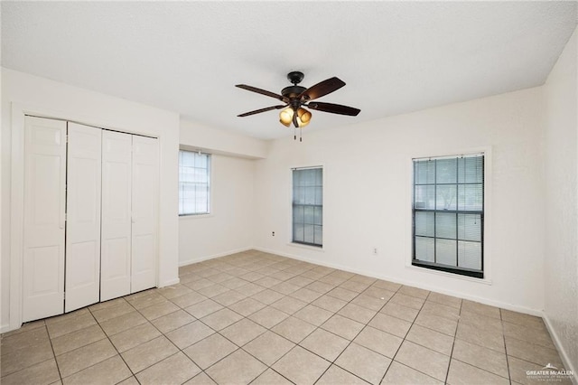 unfurnished bedroom featuring ceiling fan, a closet, and light tile patterned floors