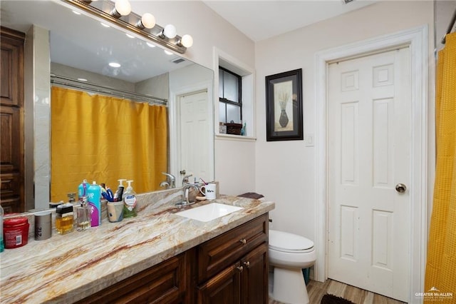 bathroom featuring hardwood / wood-style floors, vanity, toilet, and walk in shower