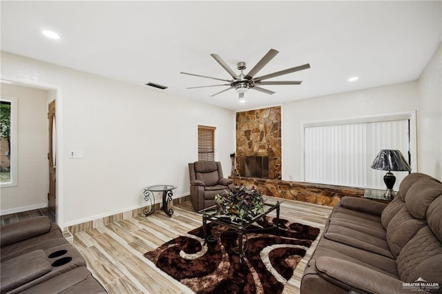 living room featuring a stone fireplace, ceiling fan, and hardwood / wood-style floors