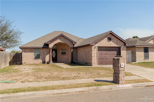 view of front of house with a front yard, fence, driveway, roof with shingles, and a garage