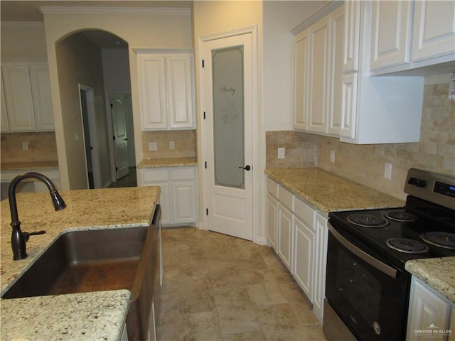 kitchen with electric range, light stone countertops, decorative backsplash, sink, and white cabinetry