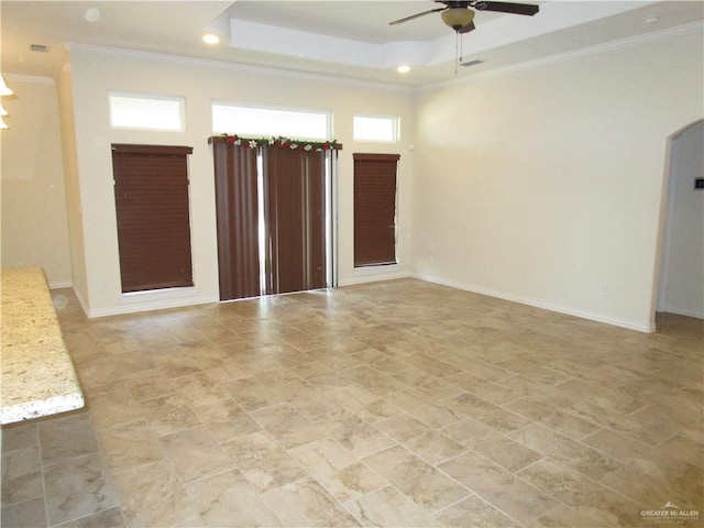 empty room with ceiling fan, a tray ceiling, and crown molding