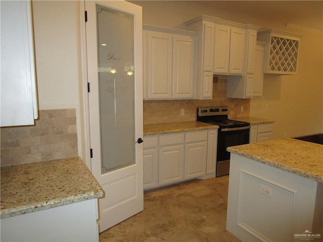 kitchen featuring white cabinets, light stone counters, electric stove, and tasteful backsplash