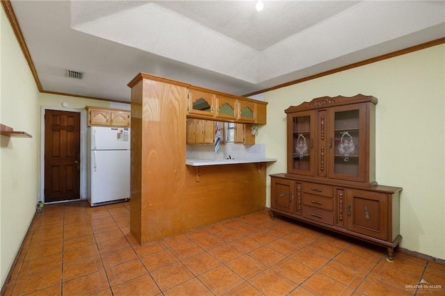 kitchen with white refrigerator, light tile patterned flooring, kitchen peninsula, and crown molding