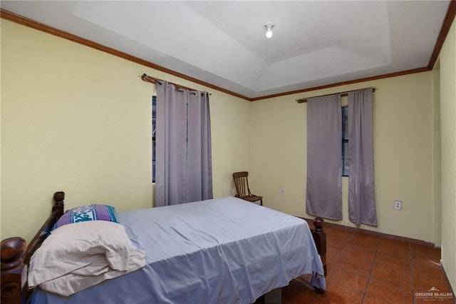 bedroom with dark tile patterned floors, crown molding, and a tray ceiling