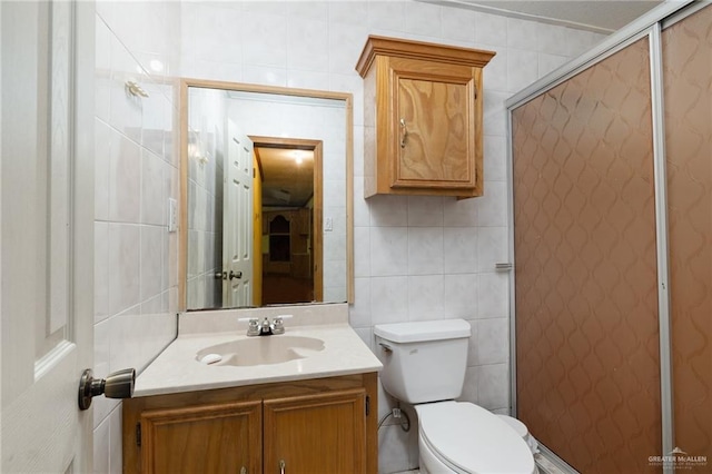 bathroom with walk in shower, vanity, toilet, and tile walls